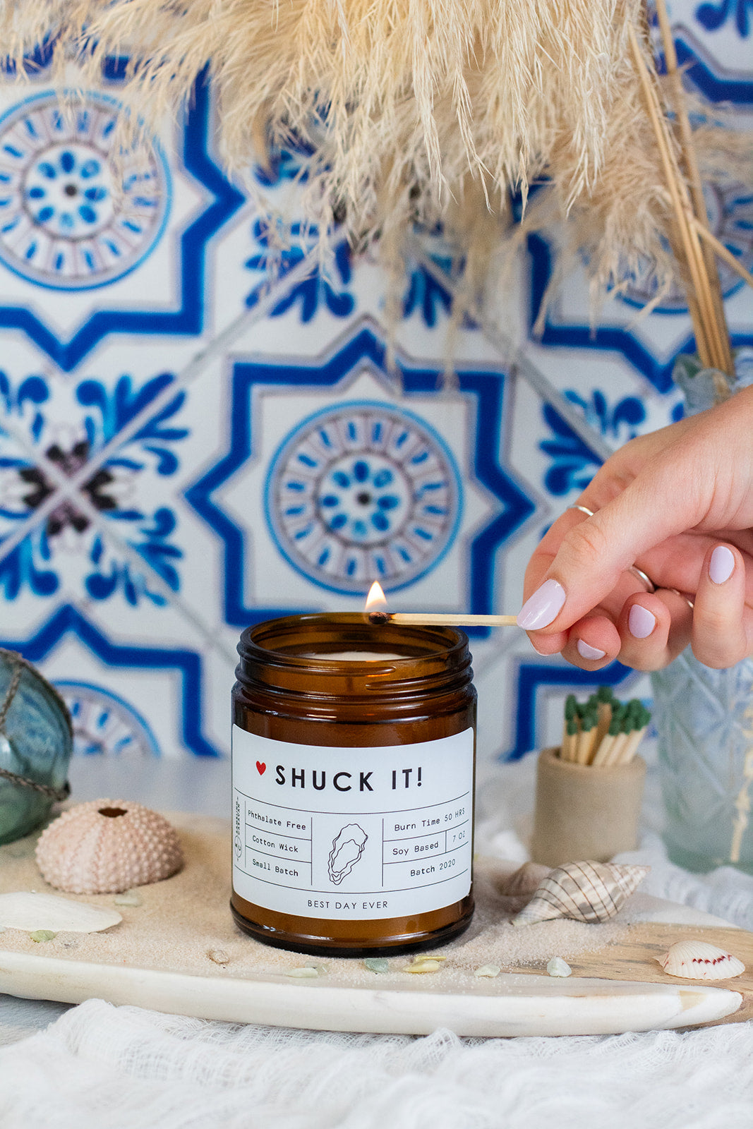 Shuck It candle being lit with a match in a coastal home.