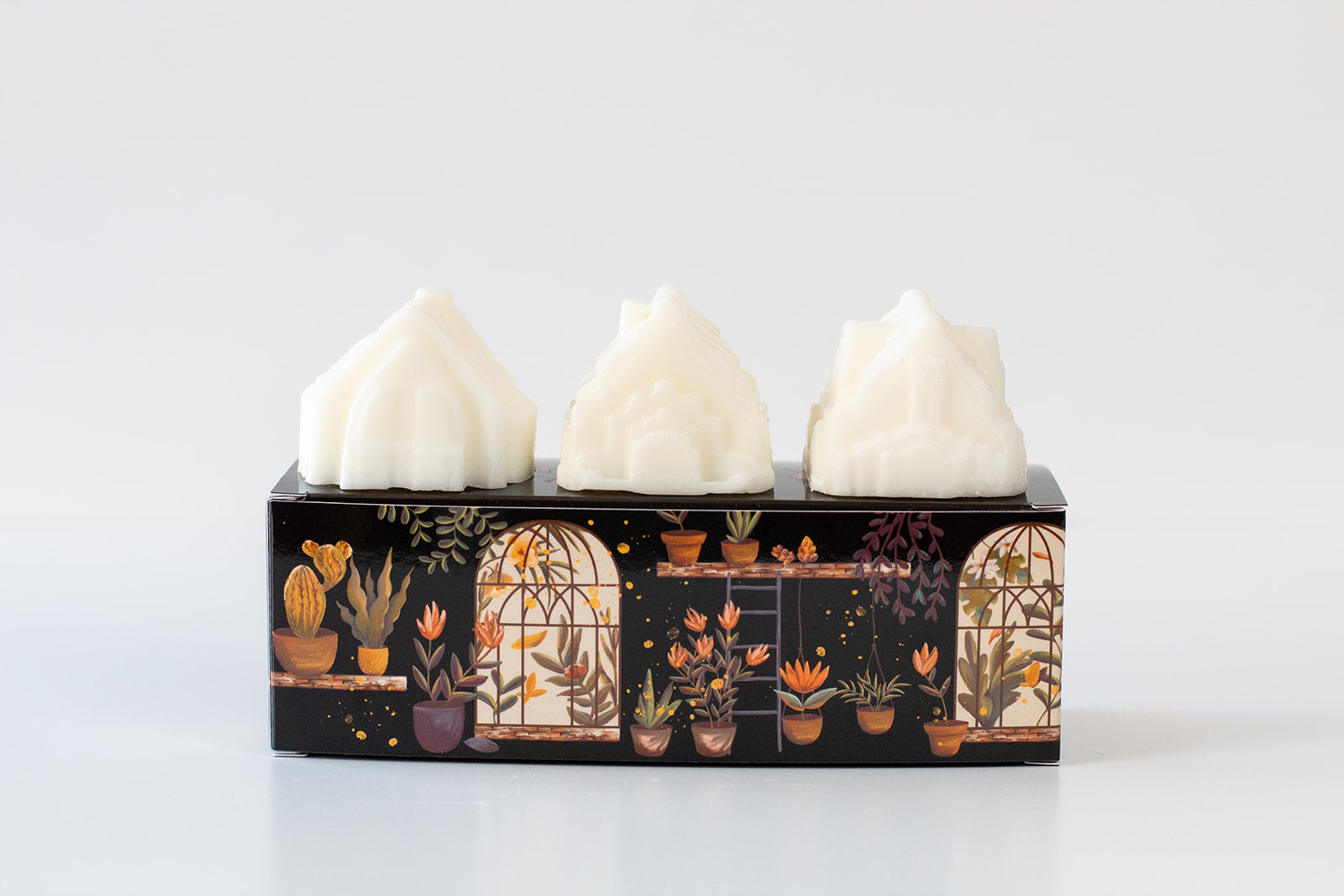 Three house-shaped wax melts on top of oblong box.