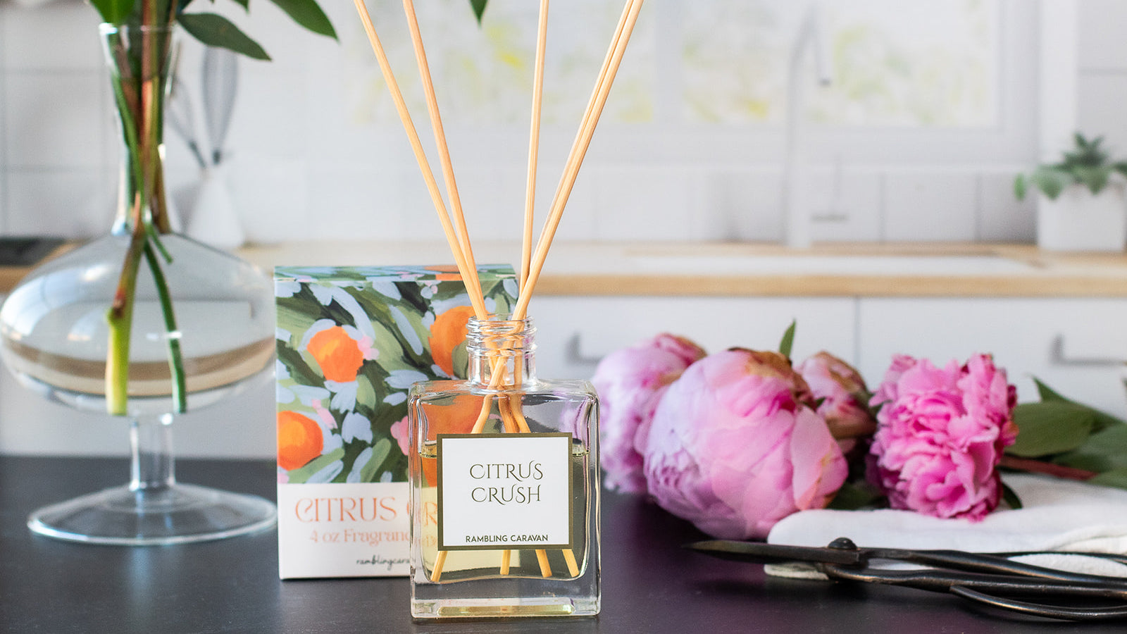Citrus crush reed diffuser in a kitchen with flowers.